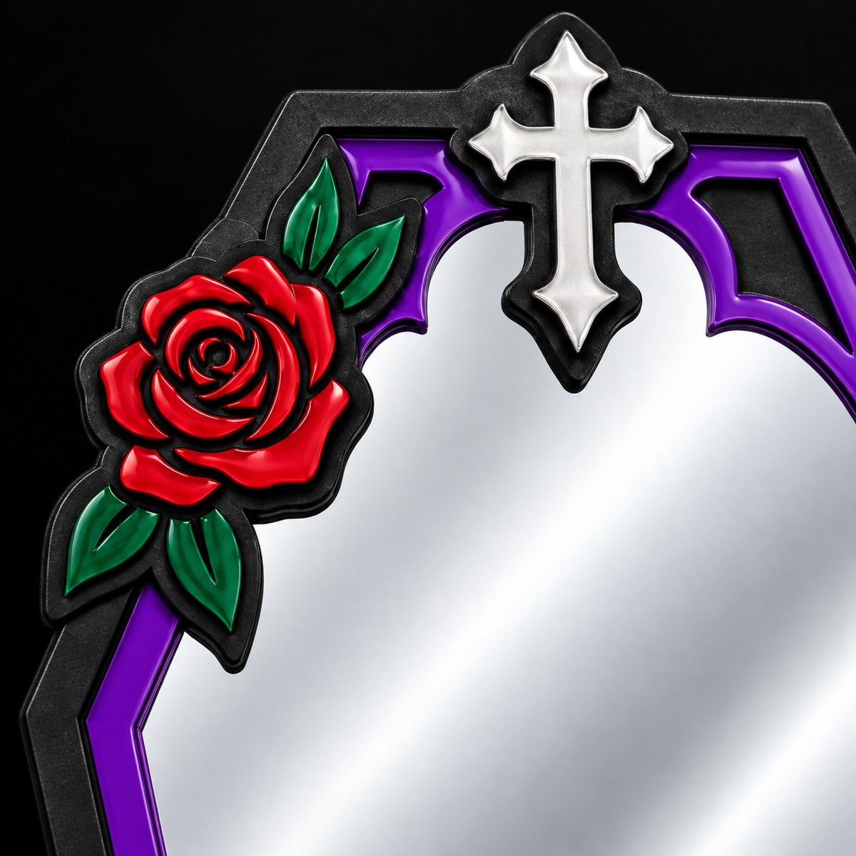 A close-up of a decorative gothic-style mirror frame featuring a red rose with green leaves on the left and a silver cross at the top, set against a black background.
