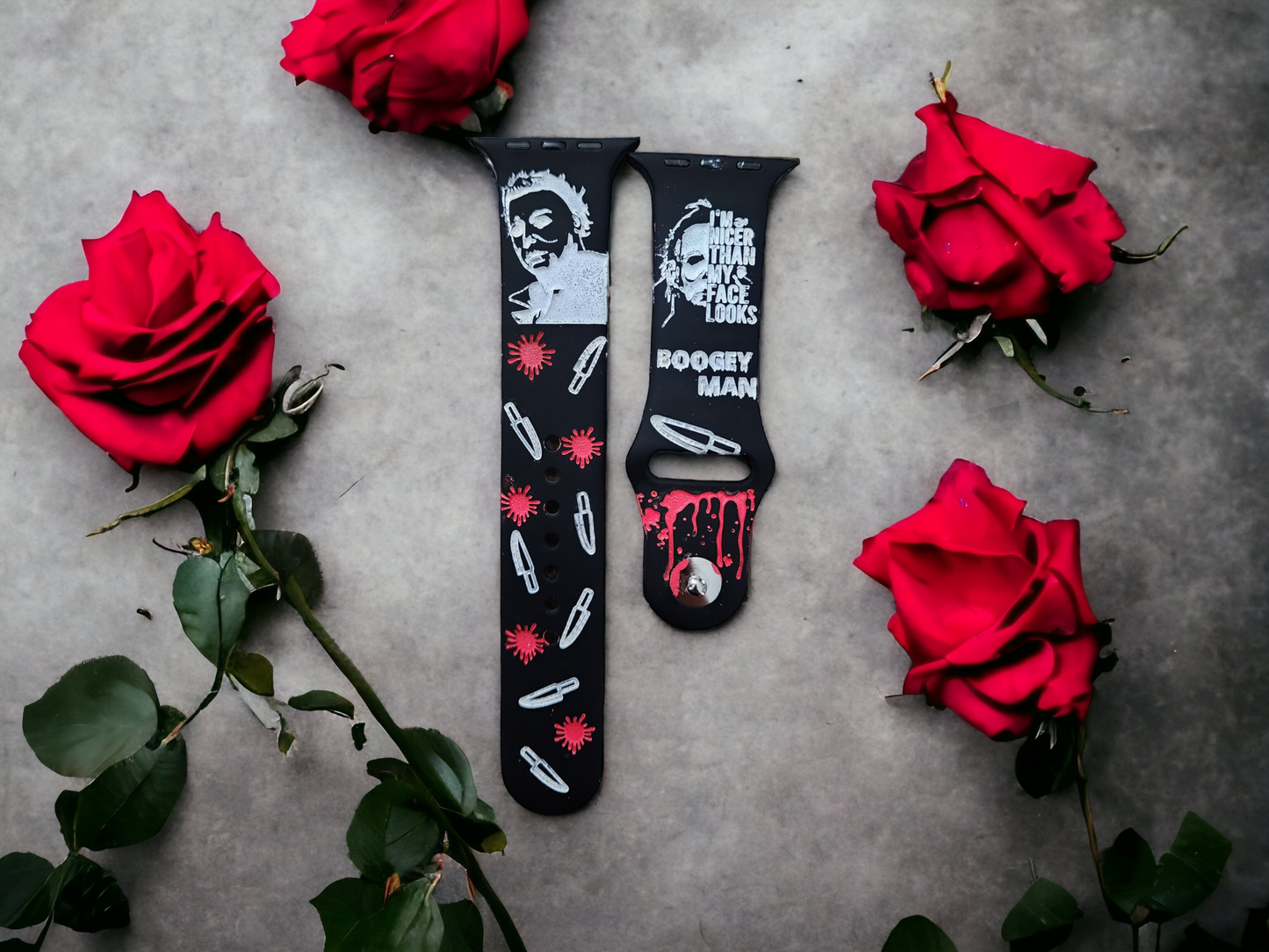 Two silicone Apple Watch bands with engraved Michael Myers character illustrations, displayed on a background with red roses.